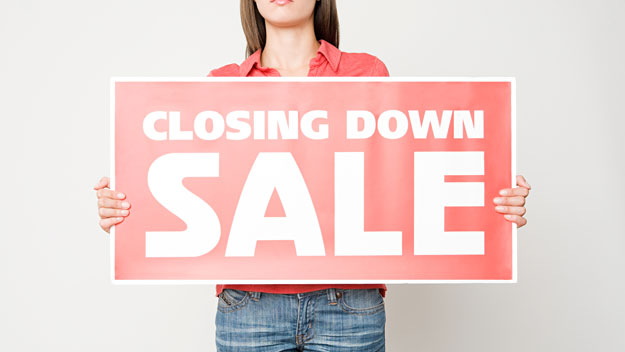 Woman holding up closing down sale sign, getty