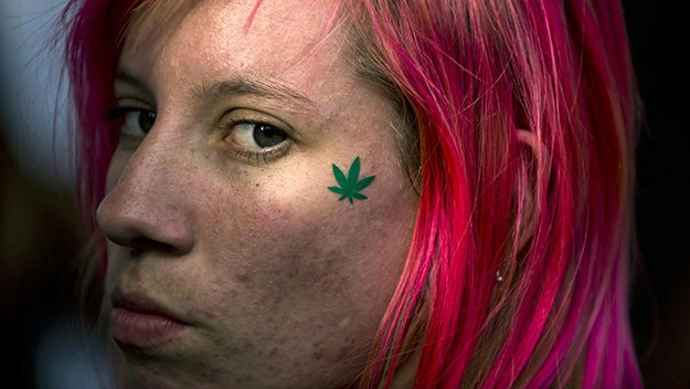 Woman with tattoo of marijuana leaf on her leaf