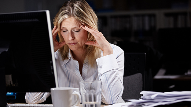 Woman with head in her hands at desk, stock image 