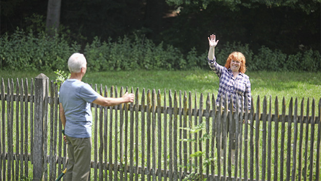 neighbours waving to each other over the fence, stock image