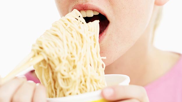 Woman eating instant noodles, stock image