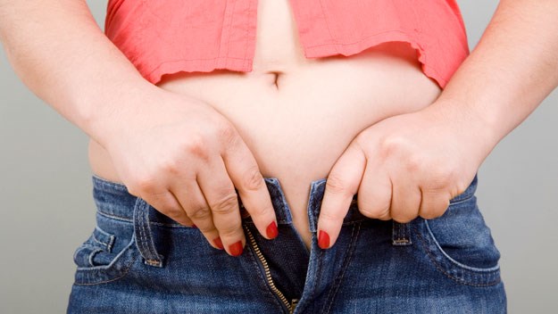 woman struggling to do up her jeans, weight gain 