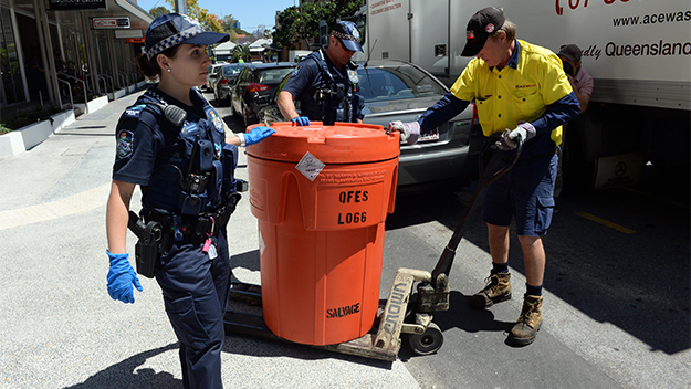 Police help a waste disposal worker move a bin out of a Teneriffe apartment
