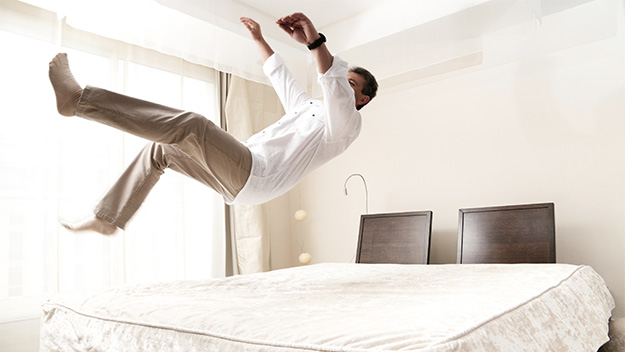 man jumping on bed, getty