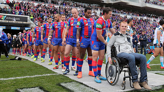 Knights players wheel Alex McKinnon onto the ground during a match between the Knights and Titans.