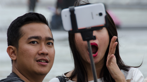 Two people taking a selfie with a selfie stick